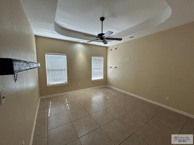 unfurnished room featuring light tile patterned floors, a raised ceiling, and ceiling fan