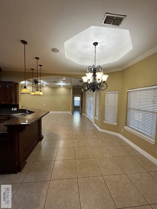 unfurnished dining area with sink, light tile patterned floors, and a tray ceiling