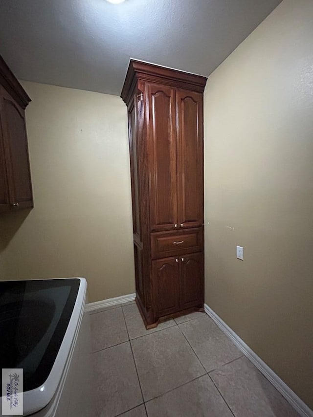 laundry area with cabinets and light tile patterned floors