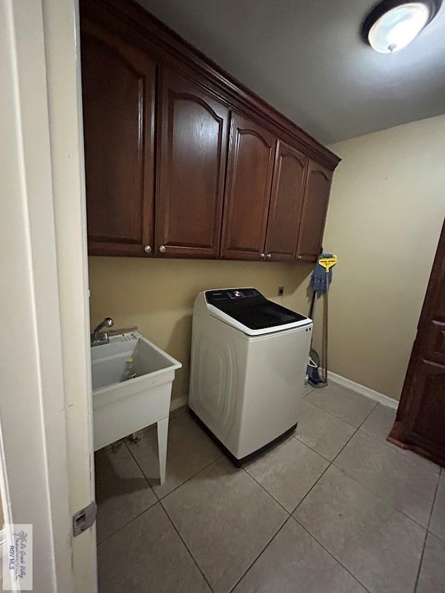 laundry area with light tile patterned flooring, cabinets, washer / dryer, and sink