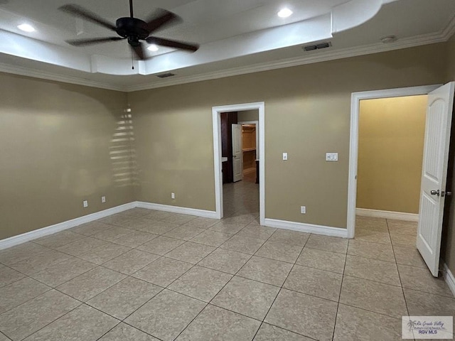 empty room with ceiling fan, ornamental molding, a raised ceiling, and light tile patterned floors