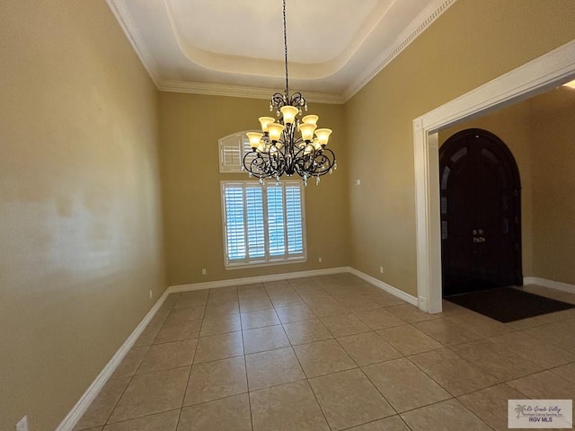 empty room with a raised ceiling, a notable chandelier, and tile patterned floors