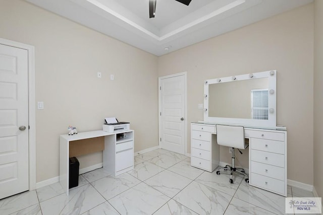 unfurnished office with a tray ceiling and ceiling fan