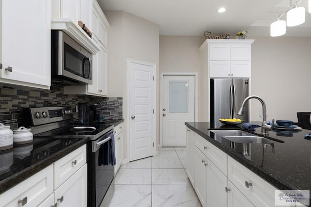 kitchen with dark stone counters, sink, appliances with stainless steel finishes, decorative light fixtures, and white cabinetry