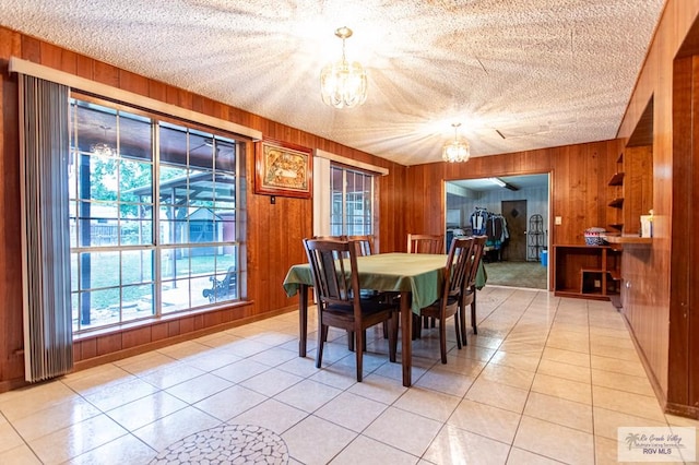 2401 E Austin Ave, Harlingen, TX 78550 - dining space featuring a chandelier, wood walls, light tile patterned flooring, and a textured ceiling