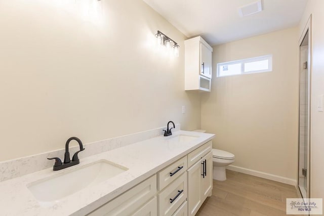 full bathroom with toilet, a sink, wood finished floors, and visible vents