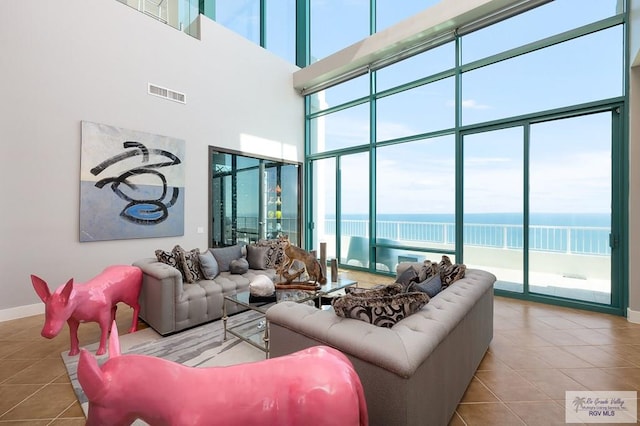 310A Padre Blvd Unit 3102, South Padre Island, TX 78597 - living room featuring tile patterned flooring, a water view, a towering ceiling, and baseboards
