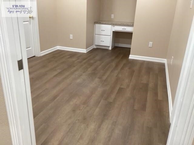 unfurnished bedroom featuring built in desk and dark hardwood / wood-style floors