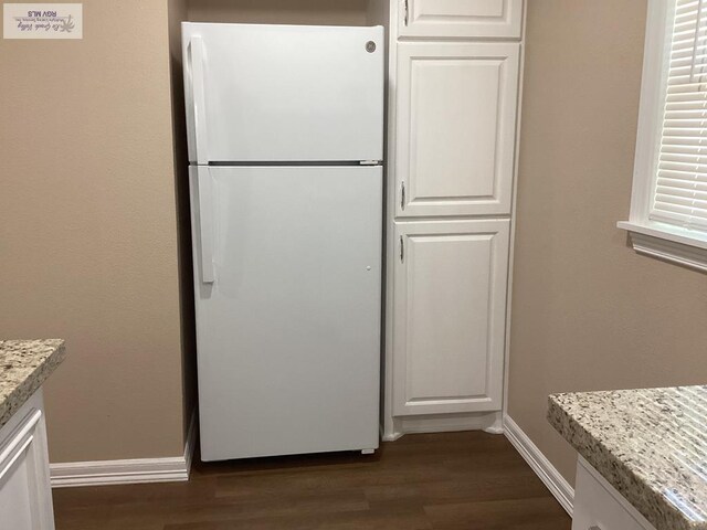 kitchen with white cabinets, white fridge, dark hardwood / wood-style flooring, and light stone countertops