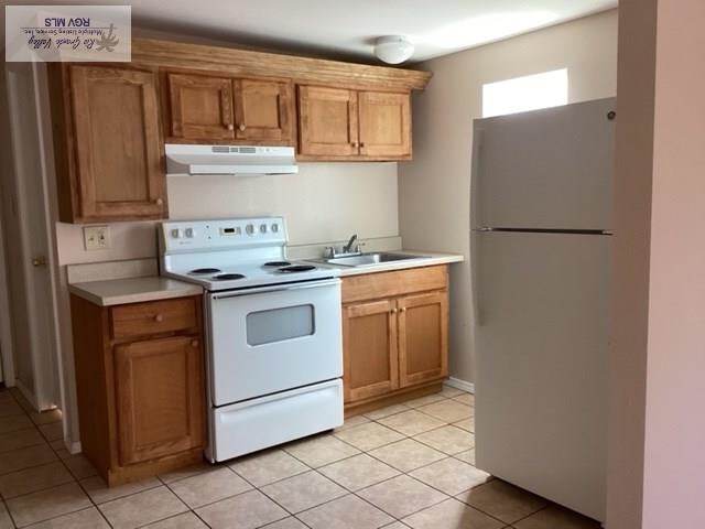 kitchen featuring sink, light tile patterned floors, and white appliances