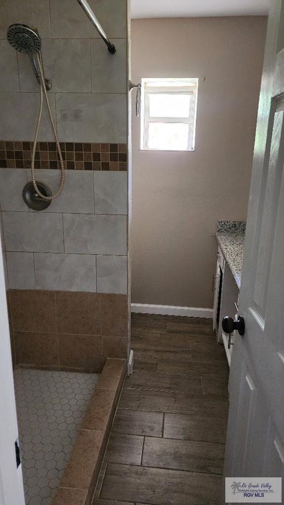 bathroom featuring tiled shower, wood-type flooring, and vanity