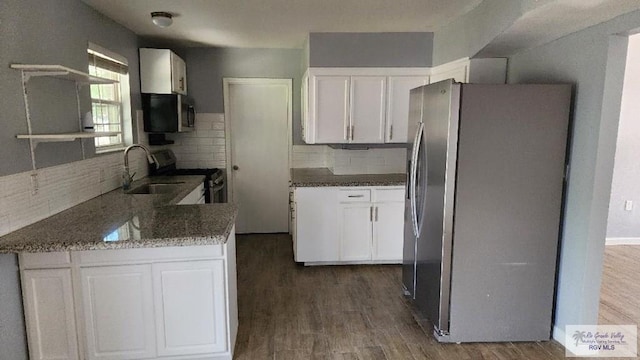 kitchen with white cabinetry, dark hardwood / wood-style floors, dark stone countertops, decorative backsplash, and appliances with stainless steel finishes