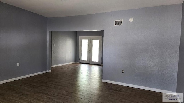 spare room featuring french doors and dark wood-type flooring