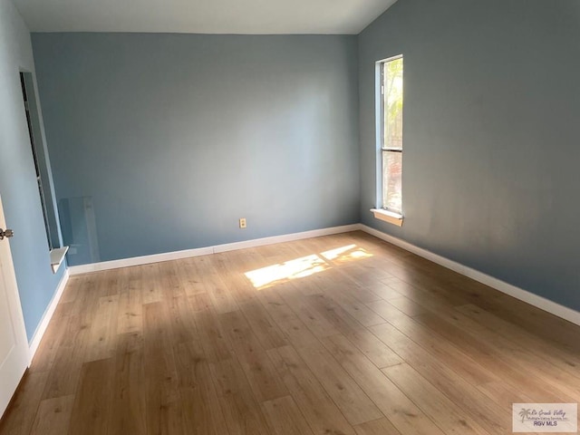 unfurnished room featuring lofted ceiling and light wood-type flooring