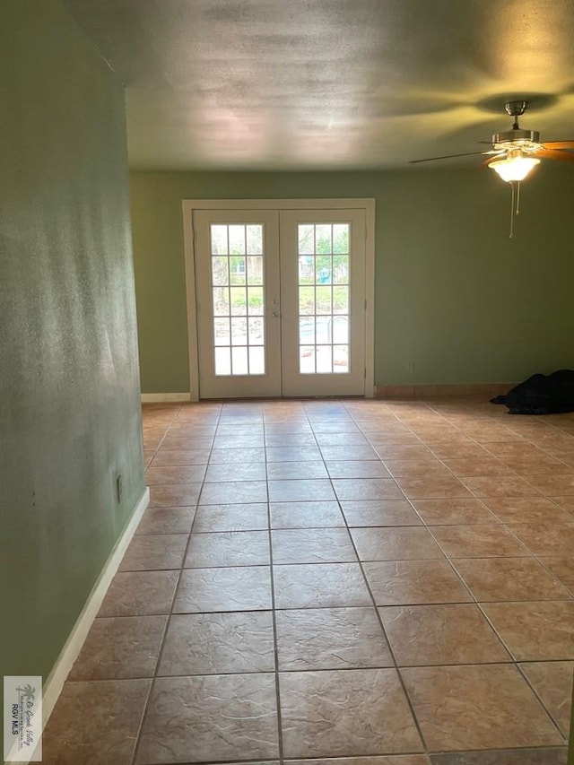 tiled spare room featuring french doors and ceiling fan