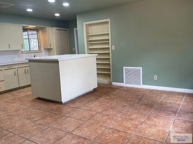 kitchen featuring a kitchen island, light tile patterned floors, decorative backsplash, and built in shelves