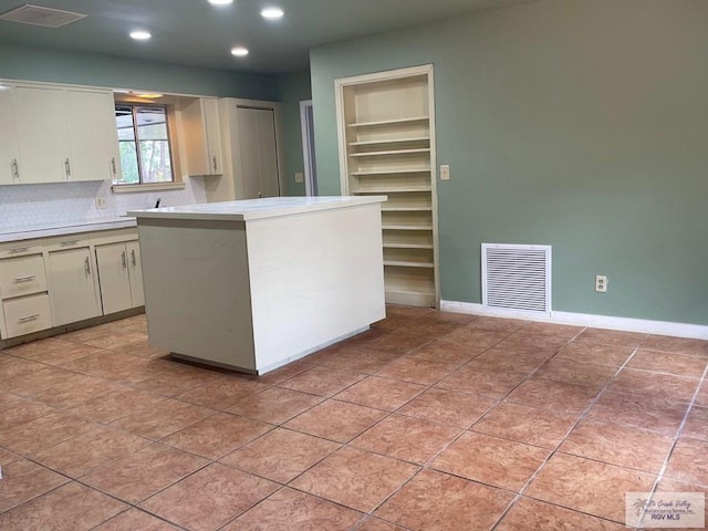 kitchen with light tile patterned flooring, tasteful backsplash, built in features, and white cabinets