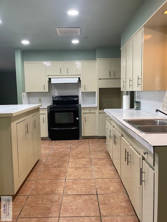 kitchen with cream cabinetry, black range with electric stovetop, backsplash, and sink