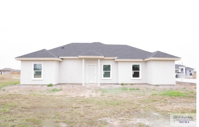 back of property with stucco siding and a shingled roof