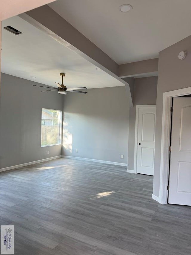 empty room with hardwood / wood-style flooring, ceiling fan, and beamed ceiling