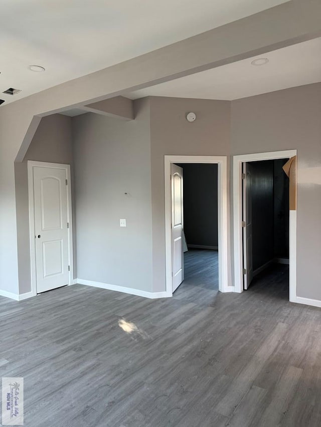 unfurnished room featuring beamed ceiling and wood-type flooring