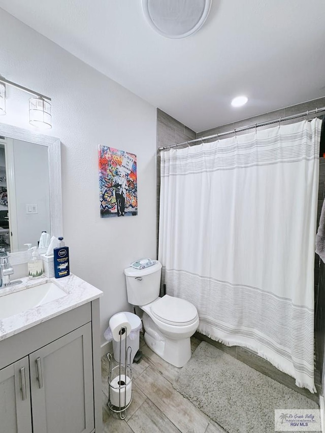 bathroom with hardwood / wood-style floors, vanity, toilet, and curtained shower