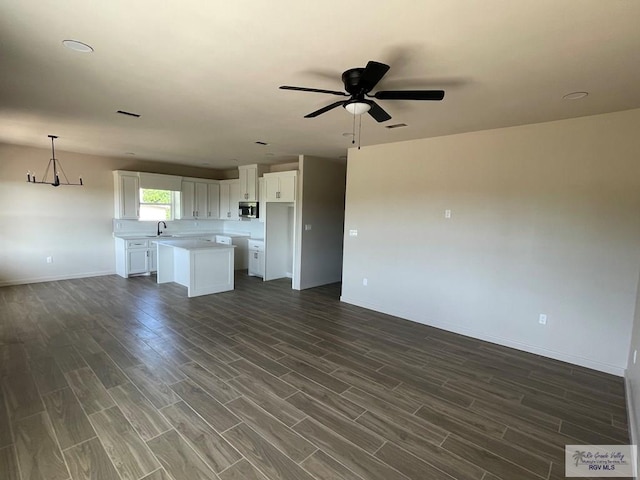 705 W Matz Ave, Harlingen, TX 78550 - unfurnished living room with dark wood-type flooring, a ceiling fan, and a chandelier