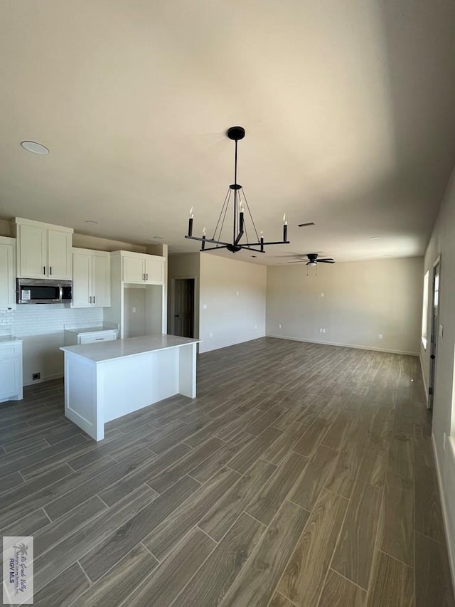 705 W Matz Ave, Harlingen, TX 78550 - kitchen featuring stainless steel microwave, a chandelier, dark wood finished floors, open floor plan, and white cabinetry