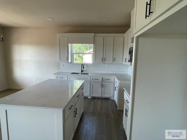 705 W Matz Ave, Harlingen, TX 78550 - kitchen with dark wood finished floors, decorative backsplash, a kitchen island, light stone countertops, and white cabinets
