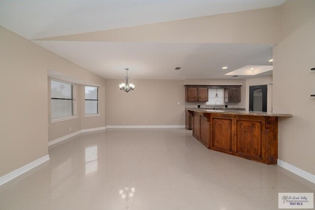 kitchen with kitchen peninsula, vaulted ceiling, a breakfast bar area, and light tile patterned flooring