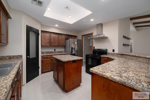 kitchen featuring stainless steel fridge, light stone counters, wall chimney exhaust hood, a center island, and black range with electric stovetop