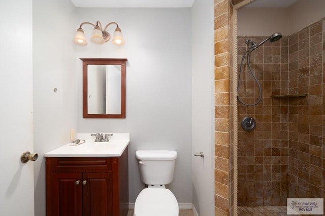 bathroom featuring a tile shower, vanity, and toilet