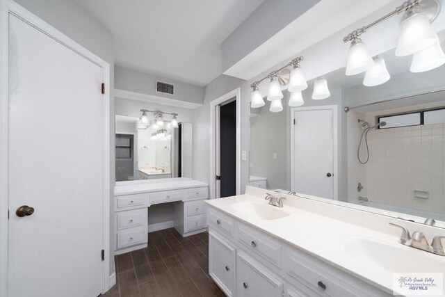 full bathroom with hardwood / wood-style floors, tiled shower / bath combo, toilet, and vanity