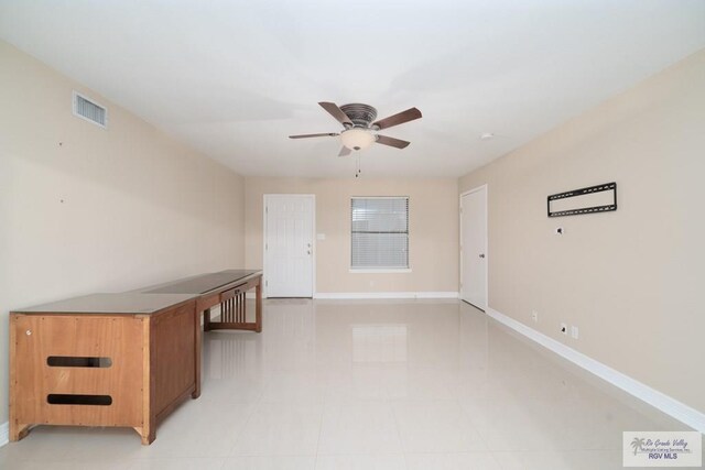 spare room with ceiling fan and light tile patterned floors