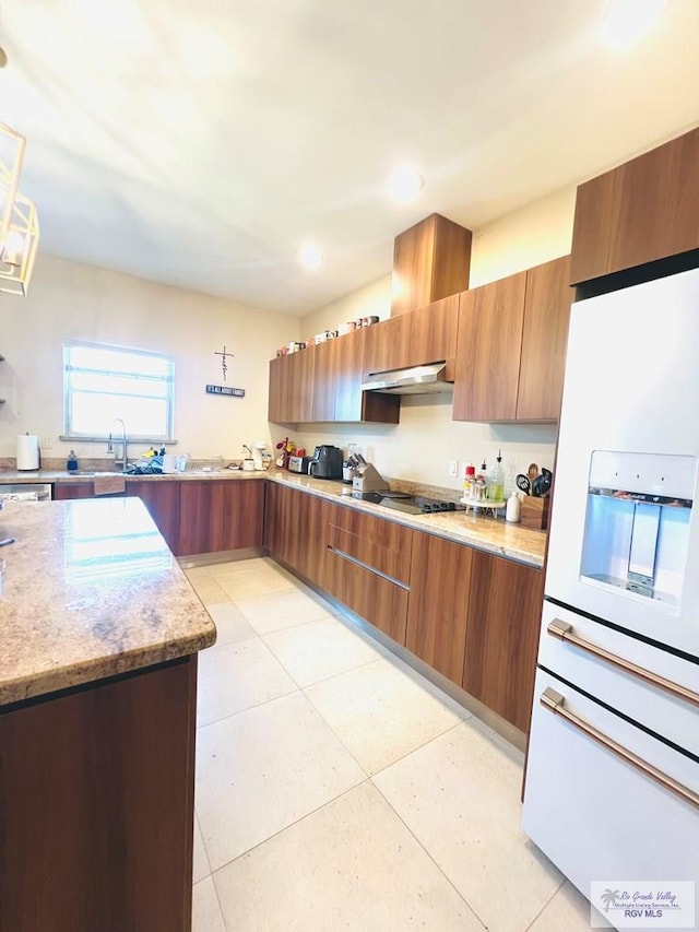 kitchen with light stone counters, light tile patterned floors, hanging light fixtures, and exhaust hood