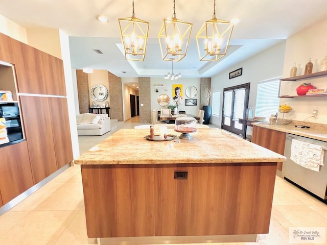 kitchen with dishwasher, a center island, a raised ceiling, pendant lighting, and a tiled fireplace