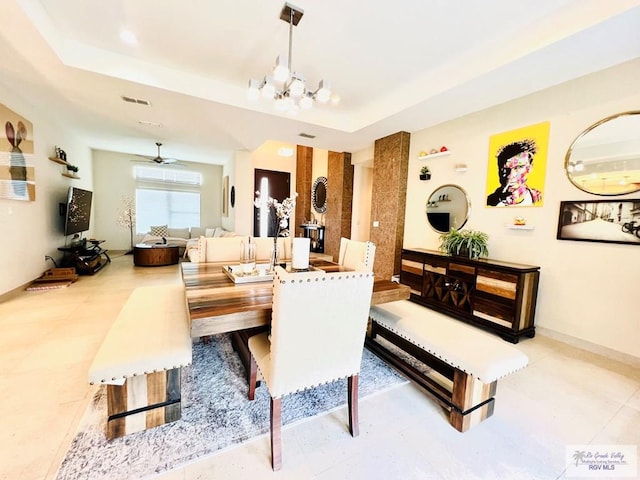 dining space featuring a raised ceiling and ceiling fan with notable chandelier