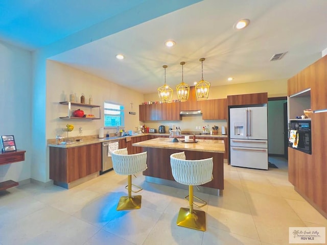 kitchen with dishwasher, a center island, decorative light fixtures, high end fridge, and light tile patterned floors