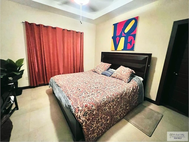 bedroom with a raised ceiling and ceiling fan