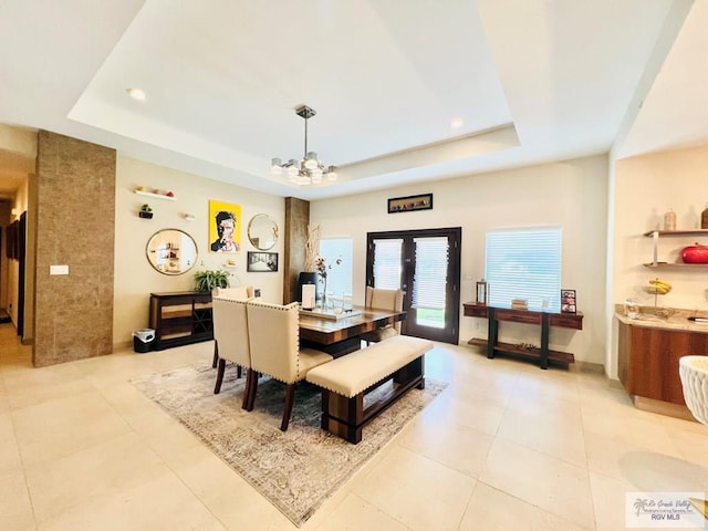 dining space featuring a tray ceiling, french doors, light tile patterned floors, and a chandelier