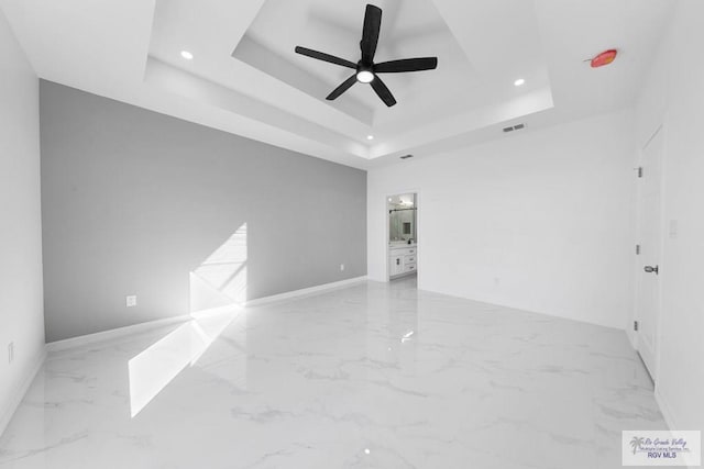 empty room featuring ceiling fan and a raised ceiling