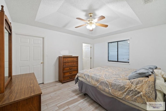 100 Pocahontas Dr Unit 100, Harlingen, TX 78552 - bedroom with a tray ceiling, wood finish floors, ceiling fan, a textured ceiling, and baseboards