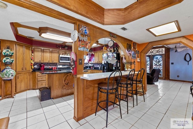 34390 Fm 732, San Benito, TX 78586 - kitchen with visible vents, a peninsula, arched walkways, stainless steel appliances, and brown cabinets
