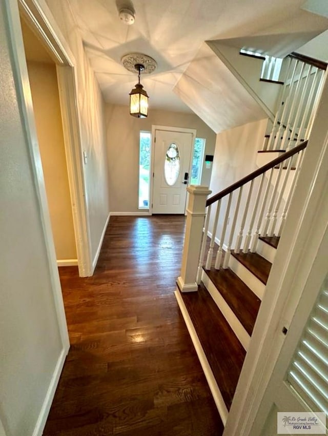 foyer entrance with dark wood-type flooring, stairway, and baseboards