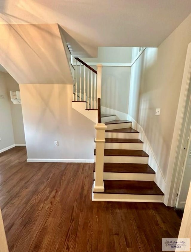 stairway featuring baseboards, lofted ceiling, and wood finished floors