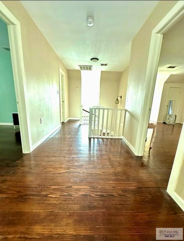 unfurnished room featuring visible vents, baseboards, and wood finished floors