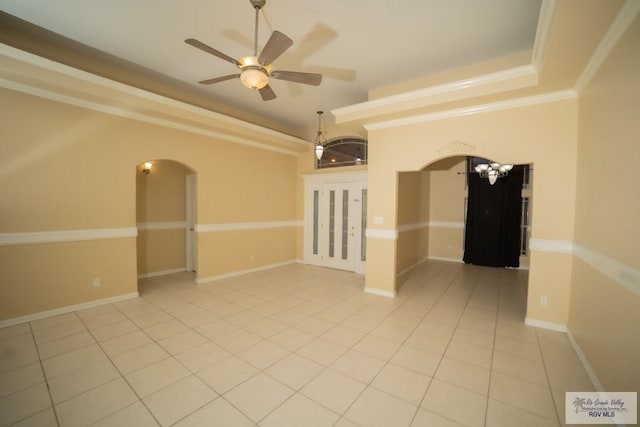 empty room with tile patterned floors, ceiling fan, a raised ceiling, and ornamental molding