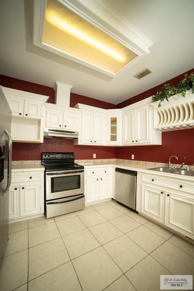 kitchen featuring white cabinetry, sink, tasteful backsplash, light tile patterned floors, and appliances with stainless steel finishes