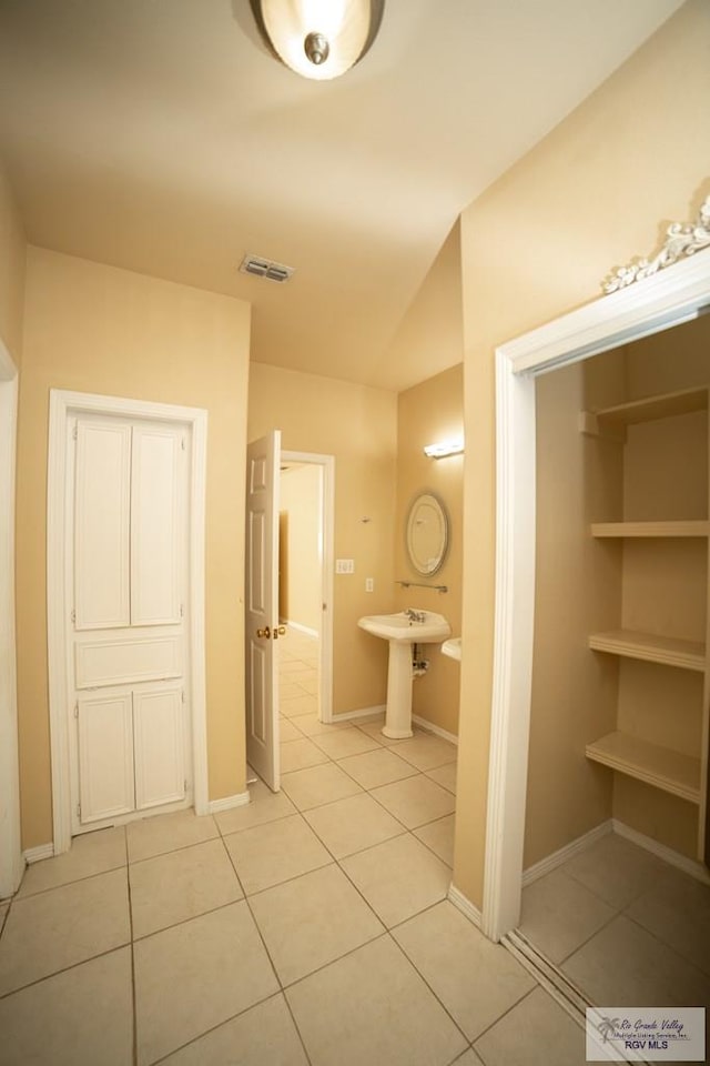 bathroom with tile patterned flooring, sink, and vaulted ceiling