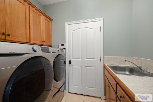 laundry room featuring washer and dryer, light tile patterned floors, cabinets, and sink